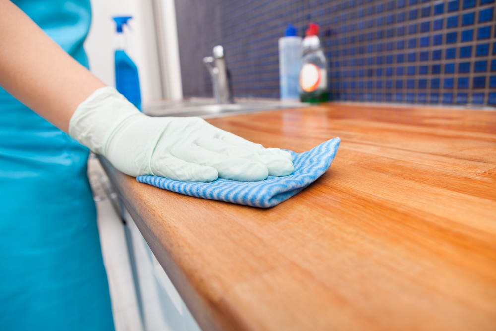 Closeup Of Young Woman Wearing Apron Cleaning Kitchen Worktop